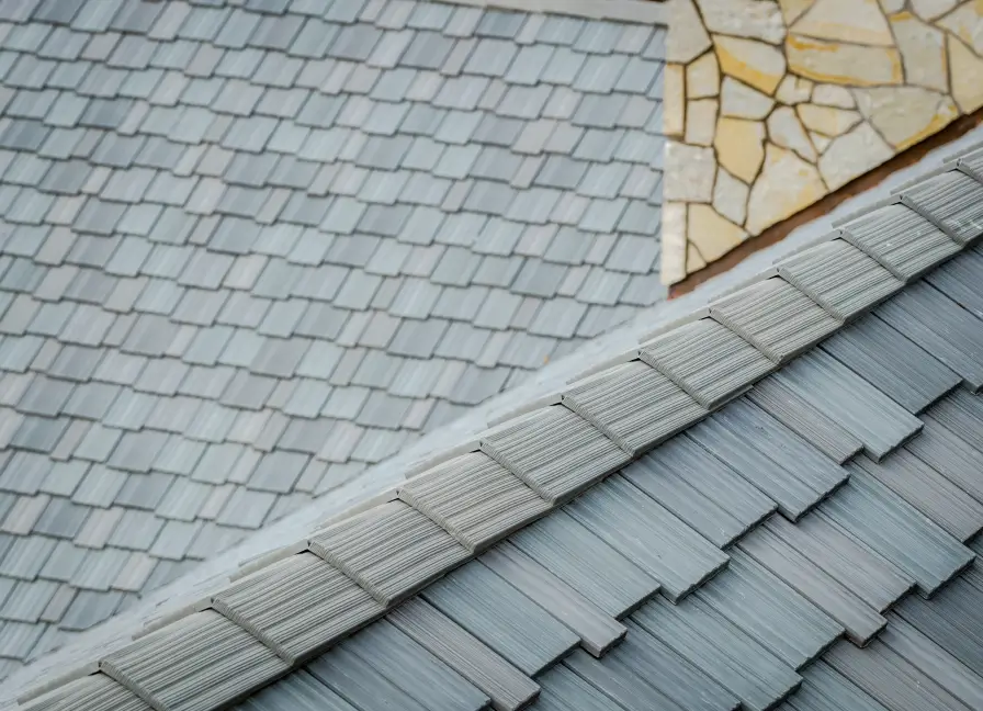 Close-up view of a gray tiled roof with overlapping shingles and a stone floor visible in the background.