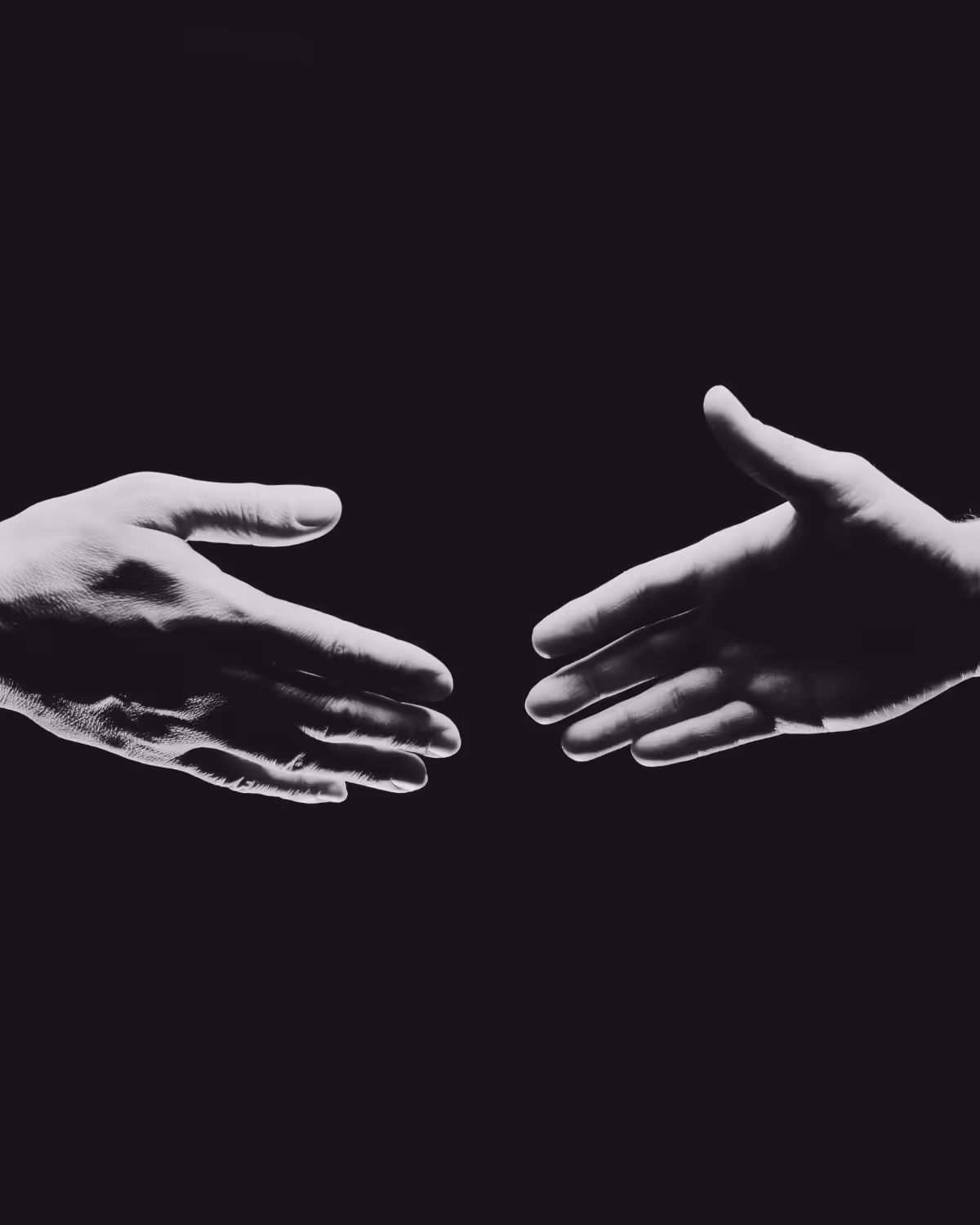 Two hands reaching towards each other for a handshake.