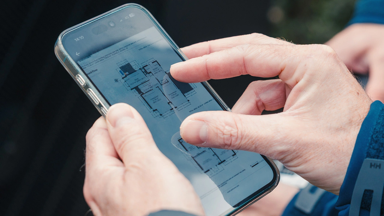 Person using a smartphone to view a detailed architectural floor plan.