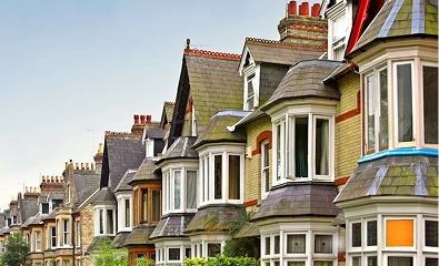 Row of traditional British terraced houses with pitched roofs, bay windows, and chimneys.