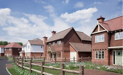 Row of modern suburban houses with brown roofs and wooden fences under a partly cloudy sky.