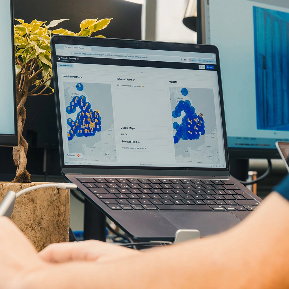 Laptop screen displaying a capacity planning dashboard with maps showing installer partners and projects clustered across the United Kingdom.