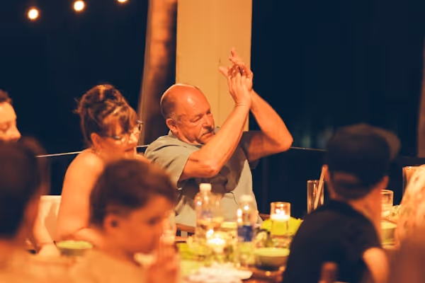 Man clapping hands at an outdoor dinner party.