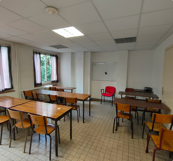 Salle de classe vide avec tables en bois, chaises, une chaise rouge et un tableau blanc.