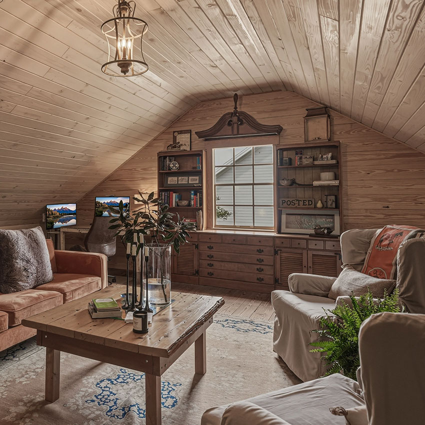Custom loft addition featuring wood-paneled walls and ceiling, built-in shelving, and cozy living space with warm, rustic finishes