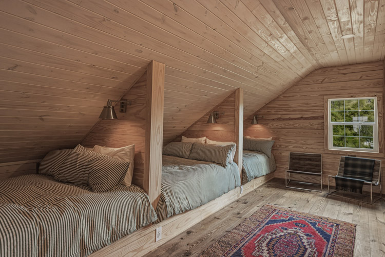 Custom loft bedroom addition with built-in beds, wood-paneled walls and ceiling, and cozy cabin-style design