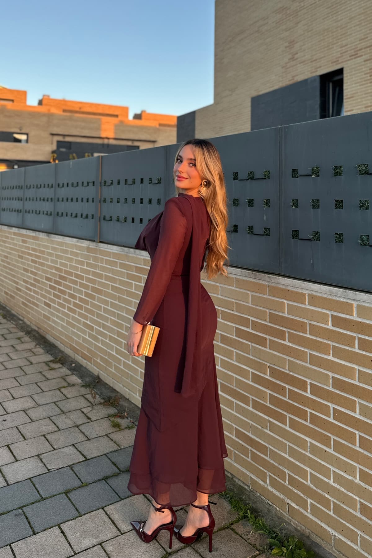 Vestido Viena de Lady Pipa, diseño midi en color berenjena con drapeado en el escote, chal al cuello y bajo asimétrico con volante de gasa, ideal para invitadas elegantes, disponible en Jointy.