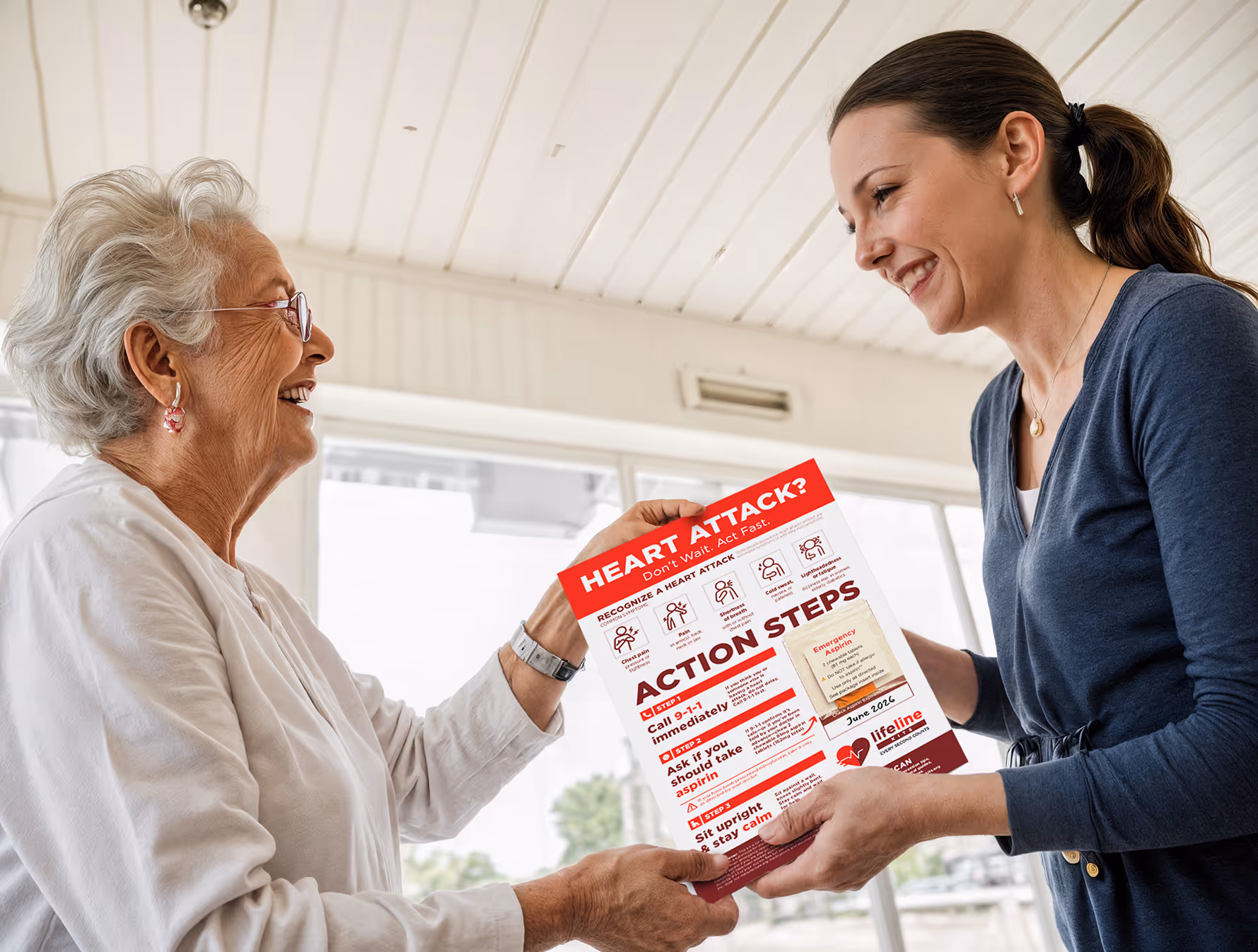 Smiling volunteer hands a LifeLine Kit with heart attack emergency steps to an elderly woman in a bright room