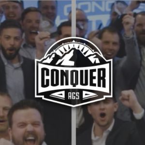 Group of enthusiastic men cheering and raising fists with a 'Conquer AGS' mountain logo overlay.