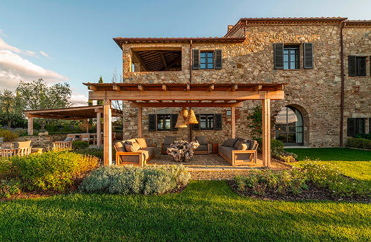 Outdoor lounge under a timber pergola with a driftwood table, surrounded by aromatic herb gardens.