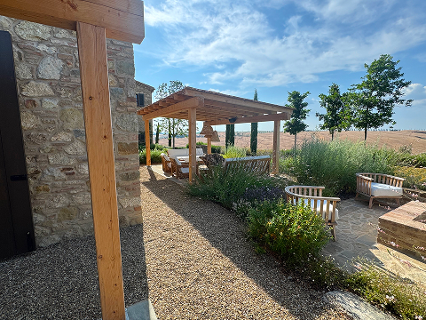 Gravel courtyard with a wooden pergola and comfortable outdoor seating in a garden.