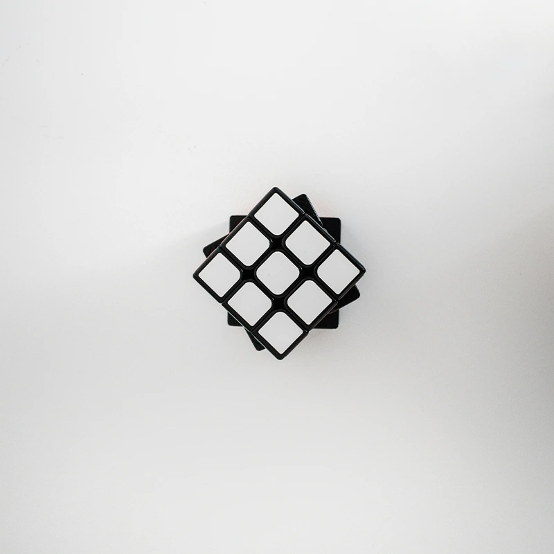 Top-down view of a scrambled black and white Rubik's Cube on a white background.