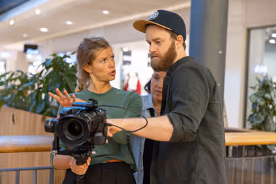 To personer diskuterer videokamera i et moderne innendørs miljø.