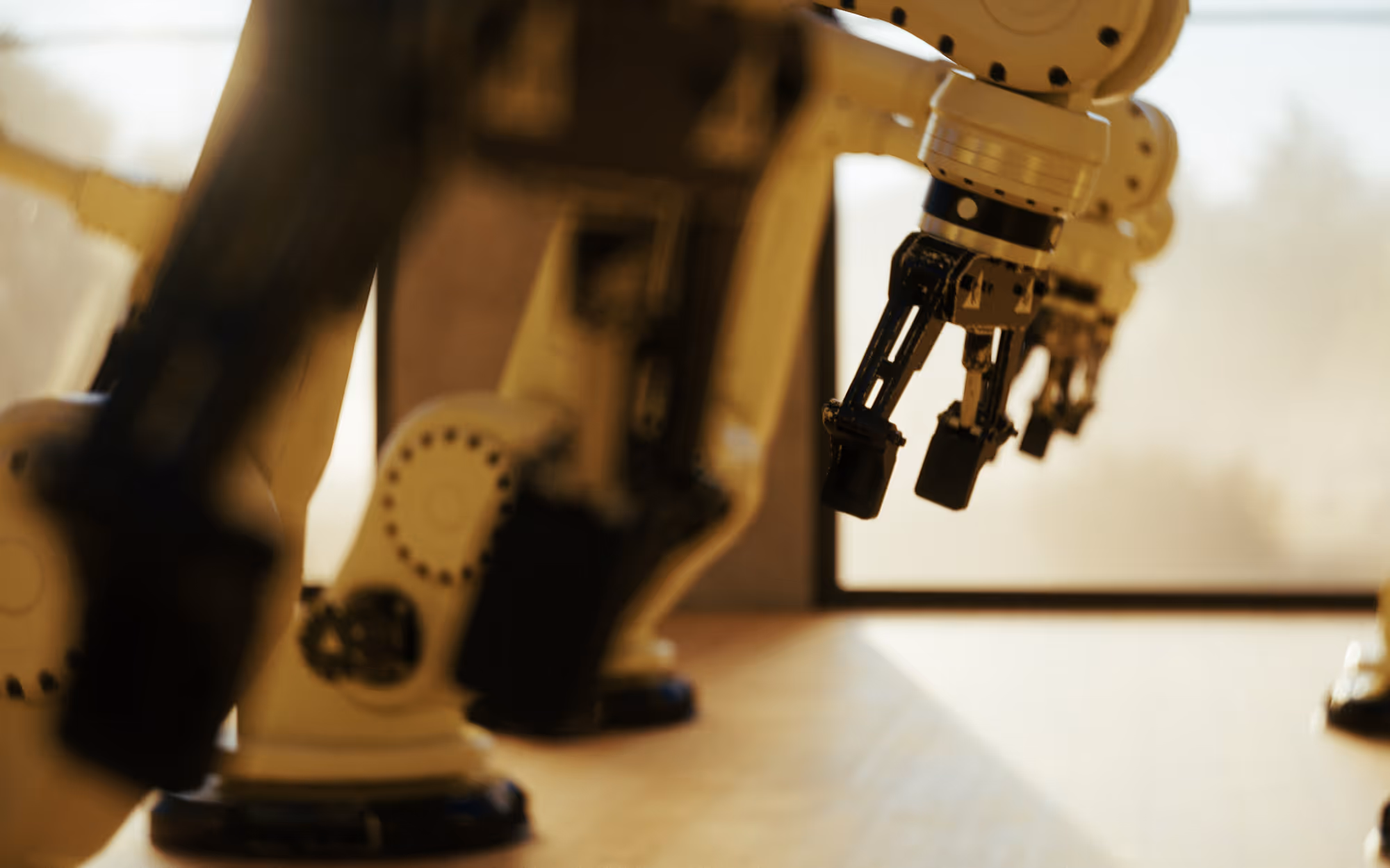 Close-up of robotic arms with claw-like grippers in a softly lit industrial setting.