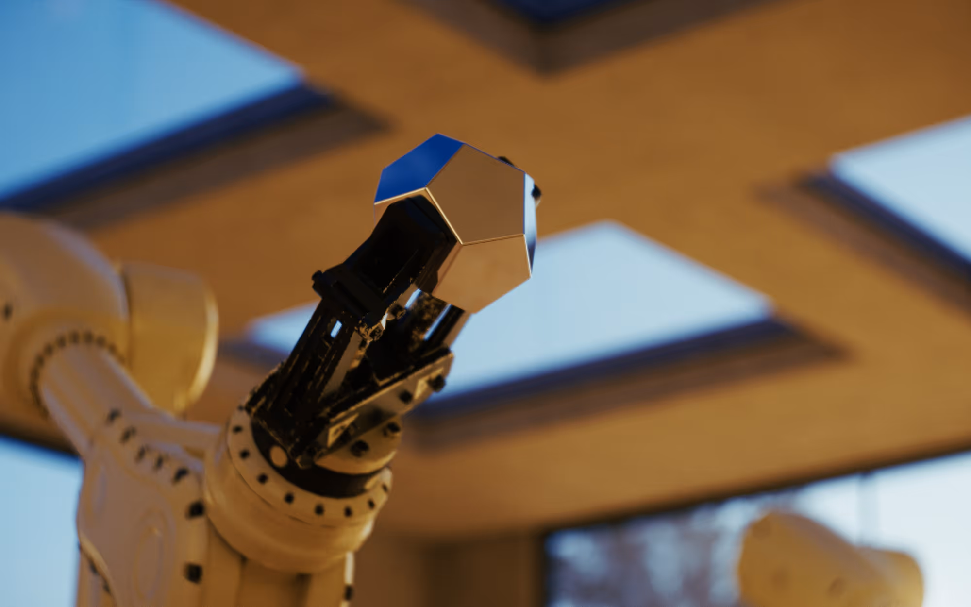 Close-up of a robotic arm holding a metallic geometric object indoors with windows in the background.