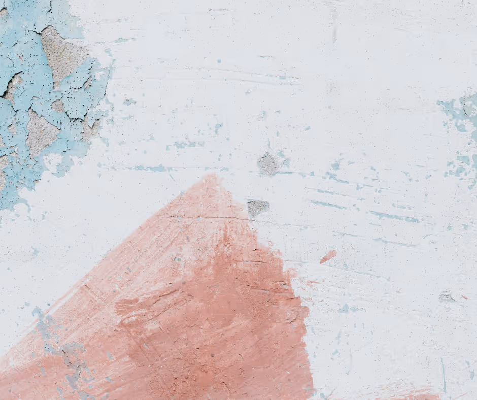 Close-up of a rough, weathered wall with peeling light blue paint and faded pink brush strokes.