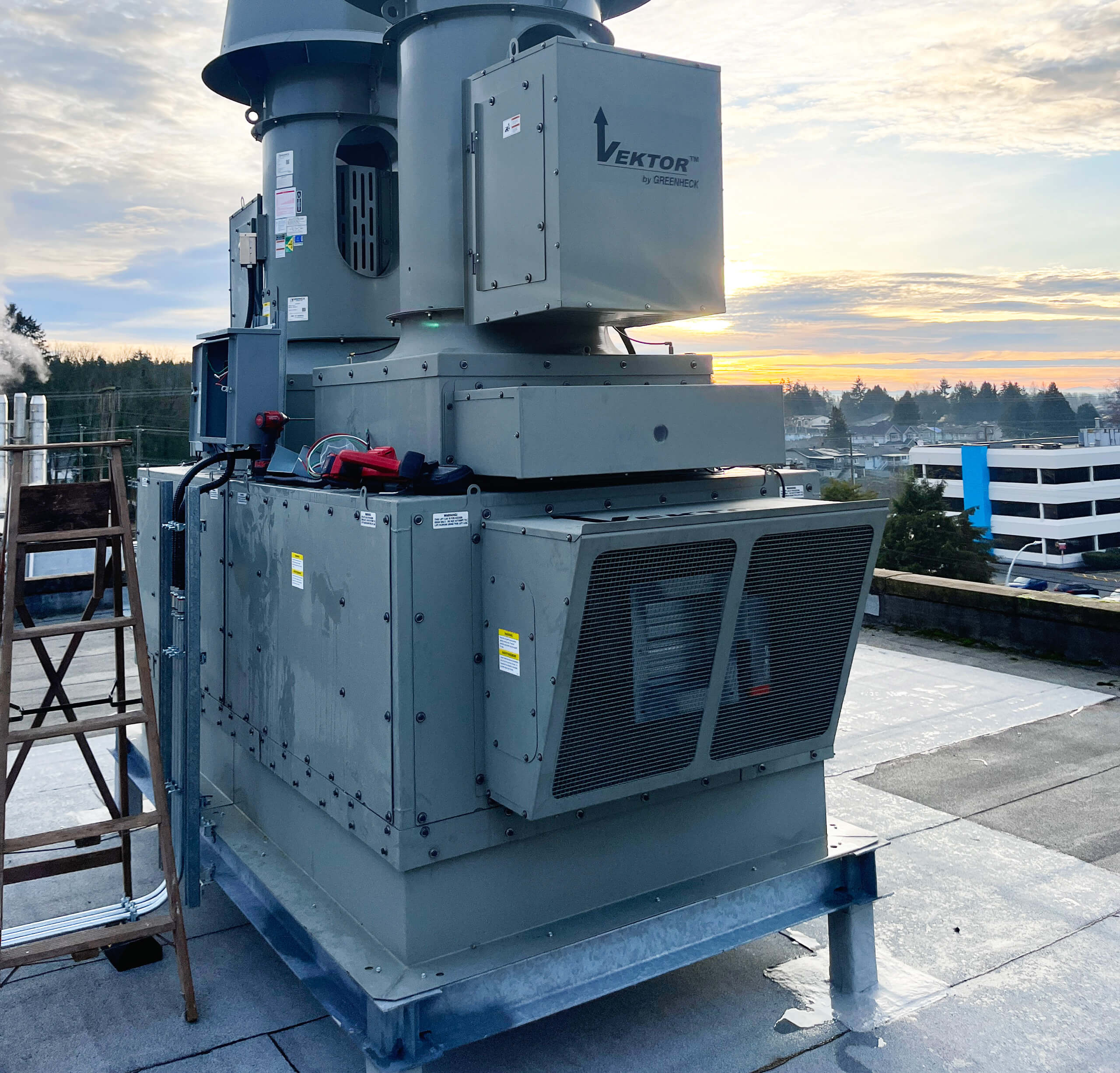 Exterior view of a high-plume laboratory or kitchen exhaust fan system (Vektor by Greenheck) installed on a rooftop curb, typical equipment reviewed during a mechanical audit.