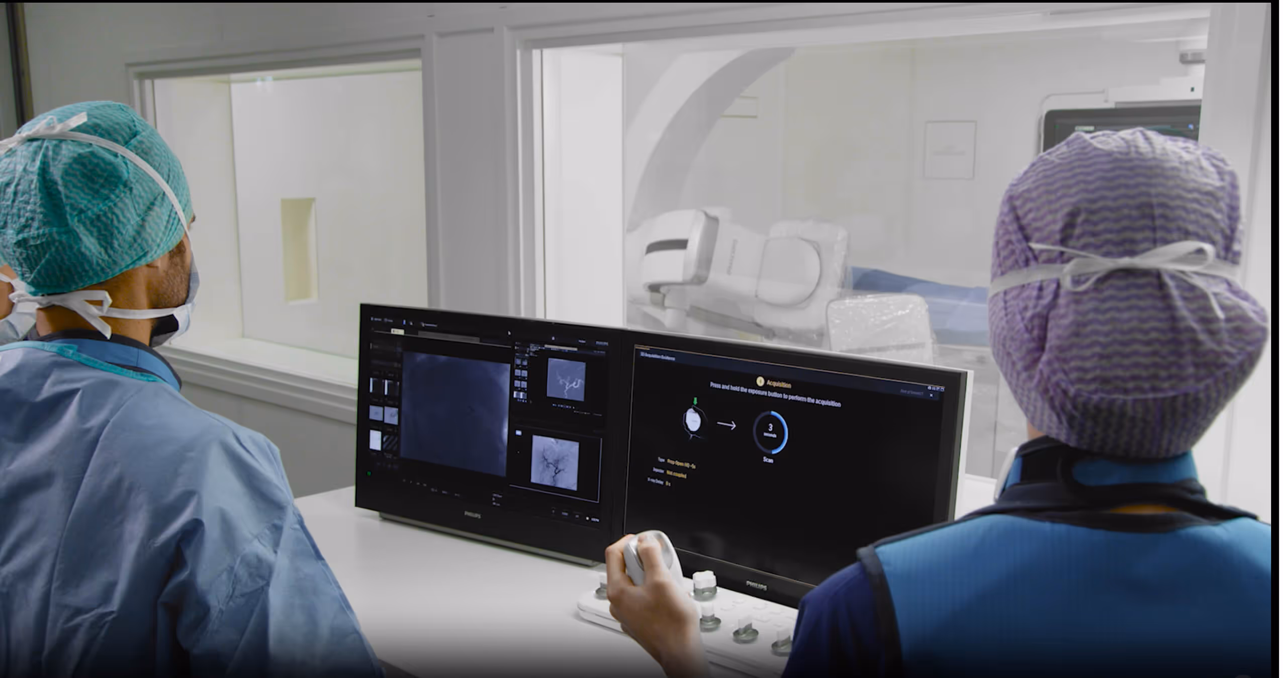Medical staff observing angiogram results on a control monitor outside the procedure room.