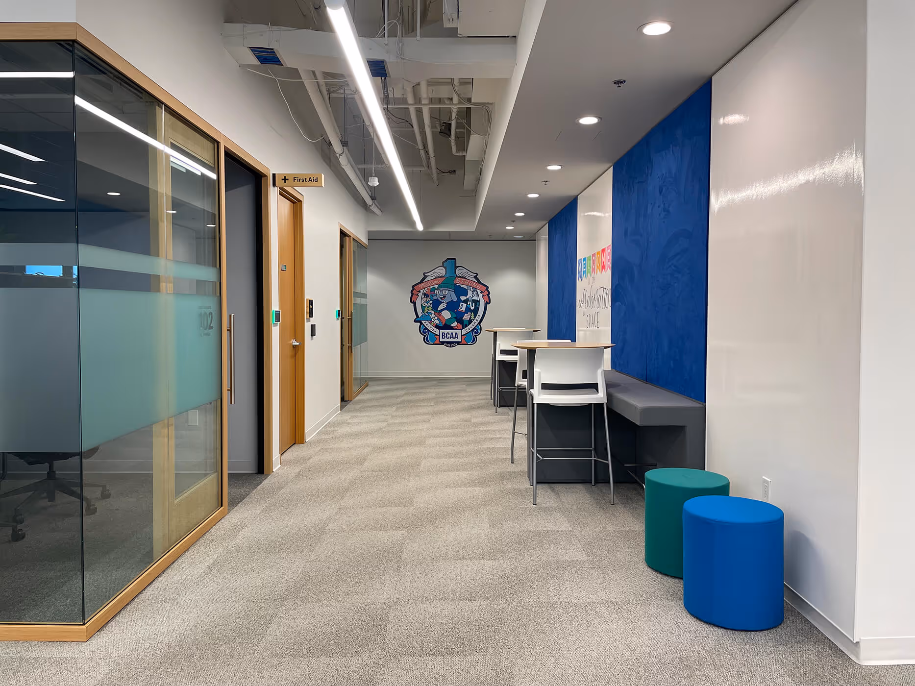 BCAA office hallway with glass walls, a blue textured feature wall, and seating.
