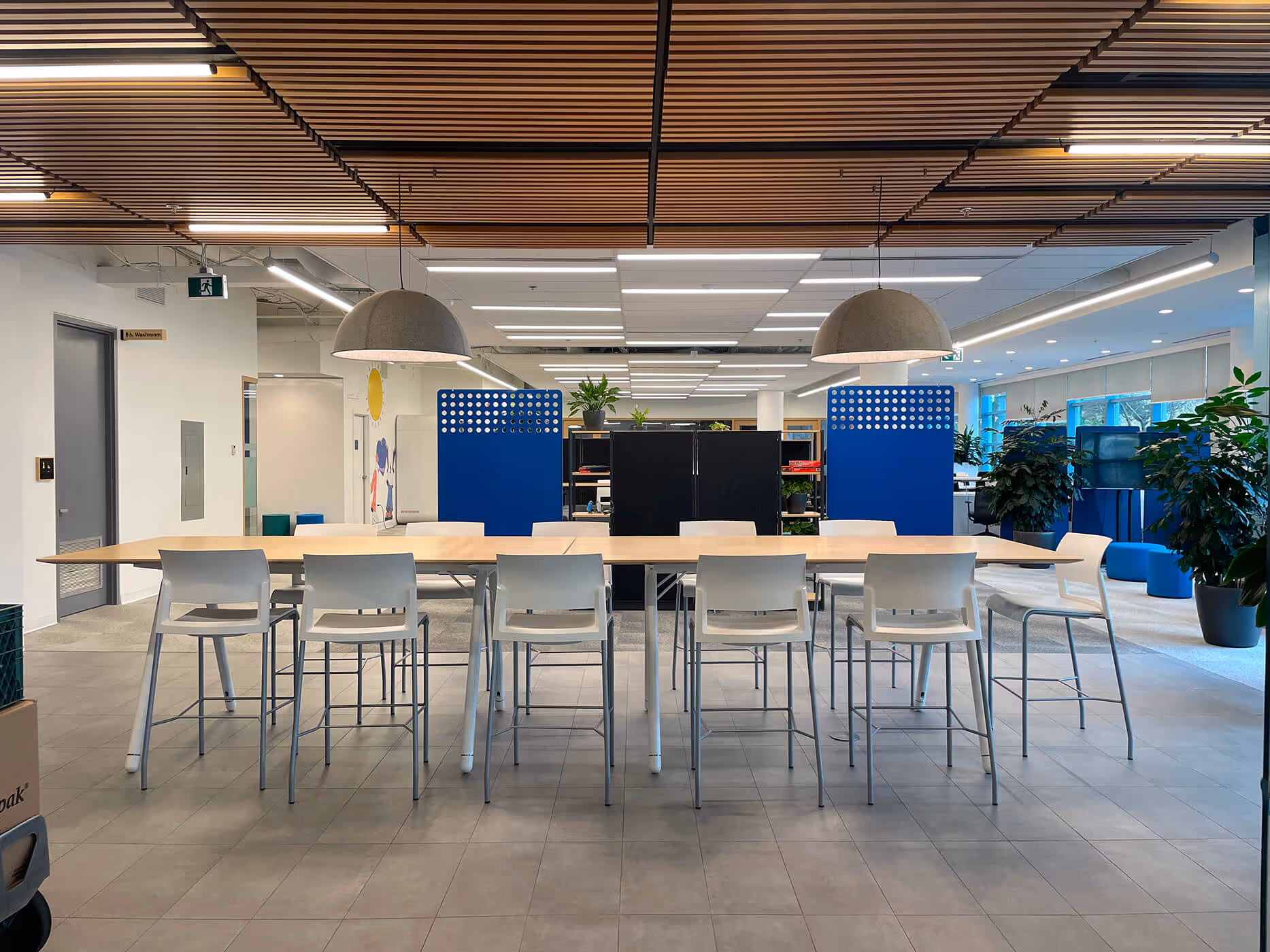 Large BCAA collaboration table beneath a wood-slat ceiling and two domed pendant lights.