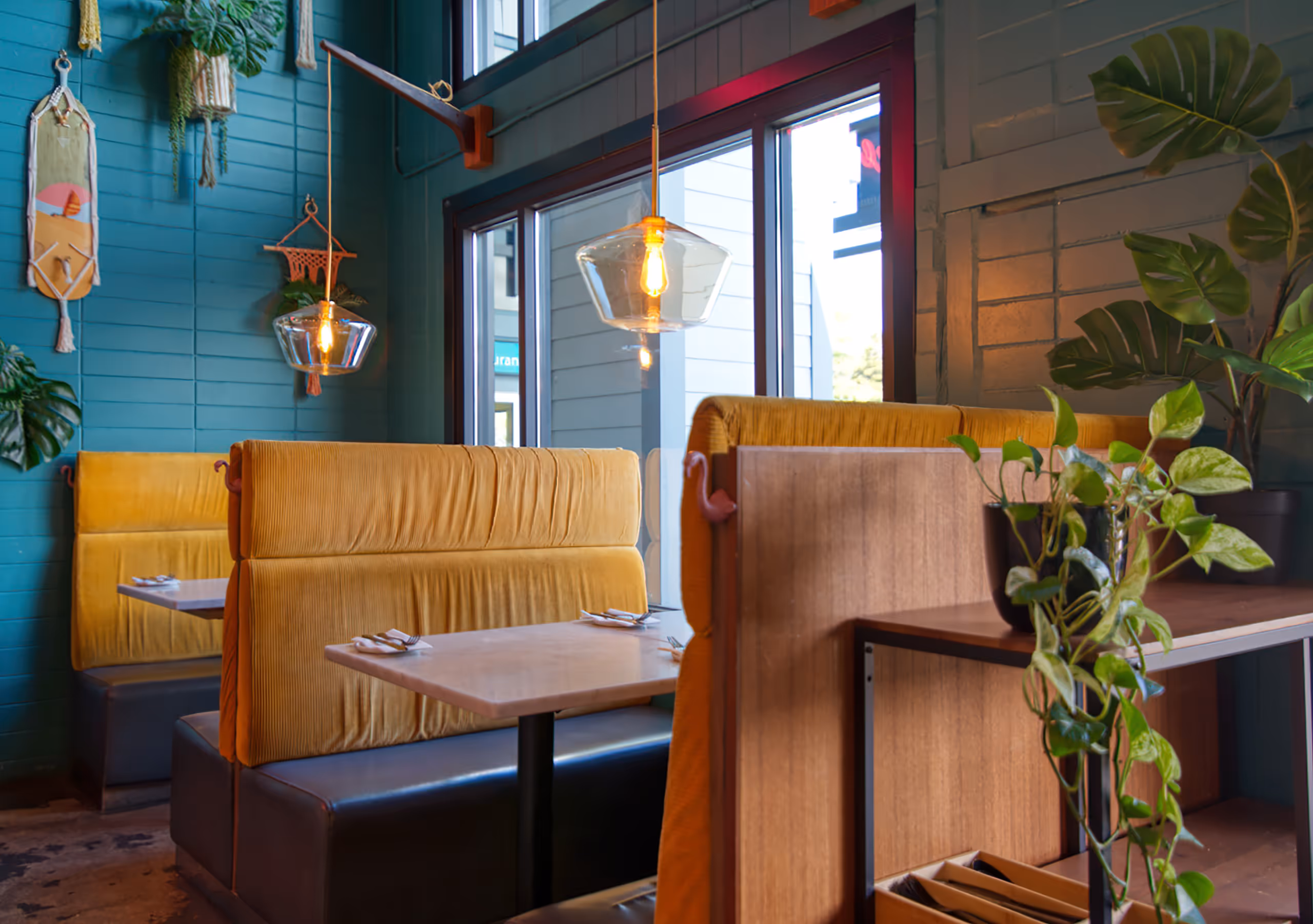Vertical detail shot of a glass pendant light above a yellow booth.