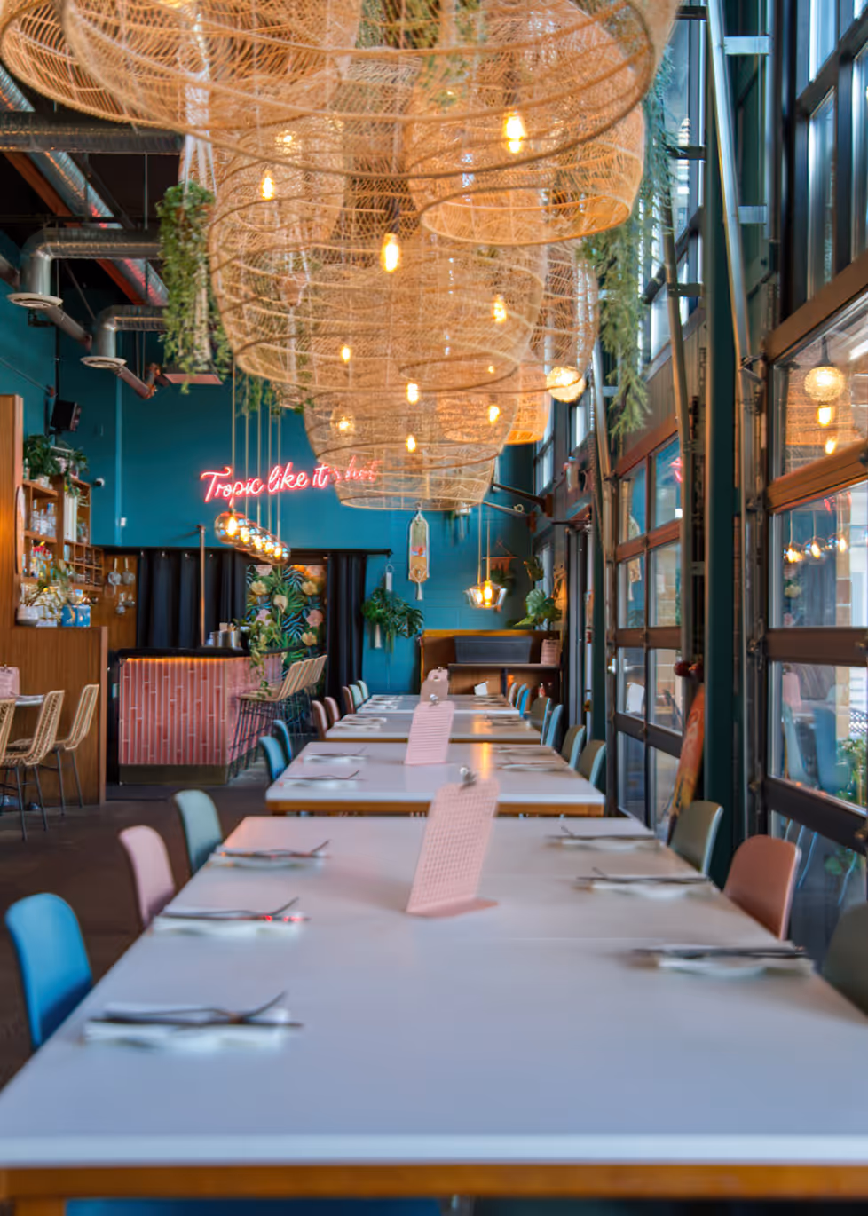 Rows of oversized woven pendant lights hanging above long dining tables.