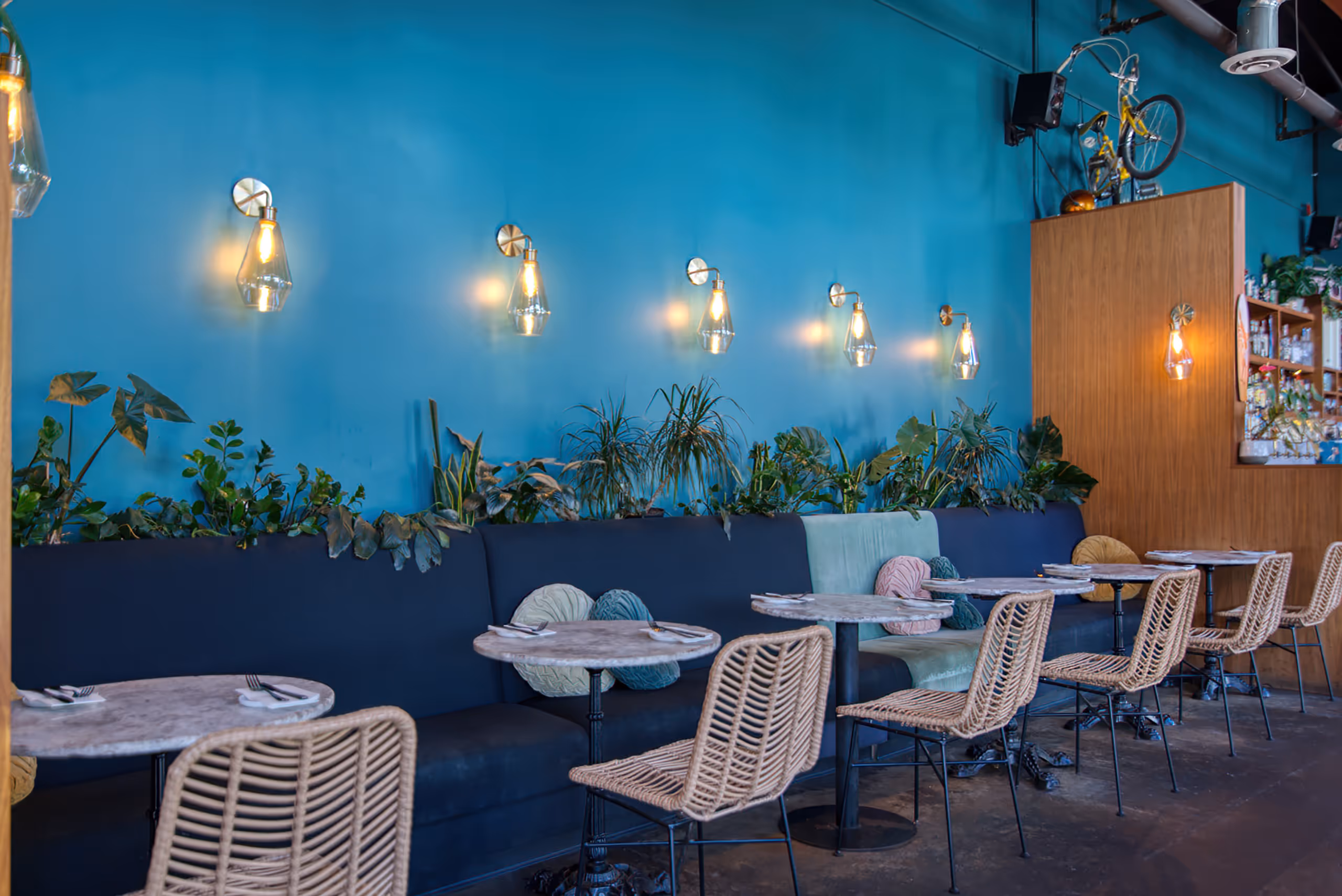 Row of gold wall sconces lighting a blue banquette dining area.