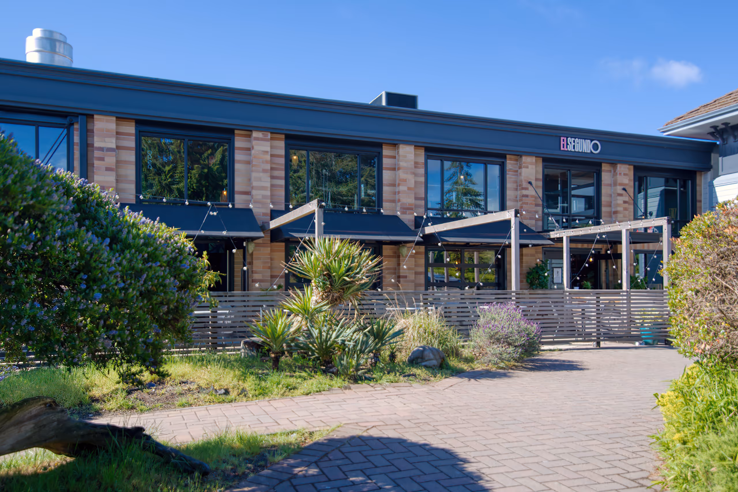 El Segundo building exterior featuring brick architecture and a string-lit patio.
