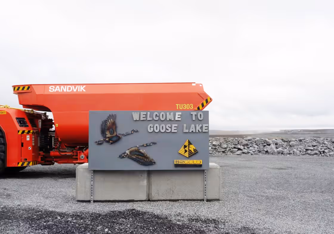 Welcome sign at Goose Lake industrial site with mining vehicle in background.
