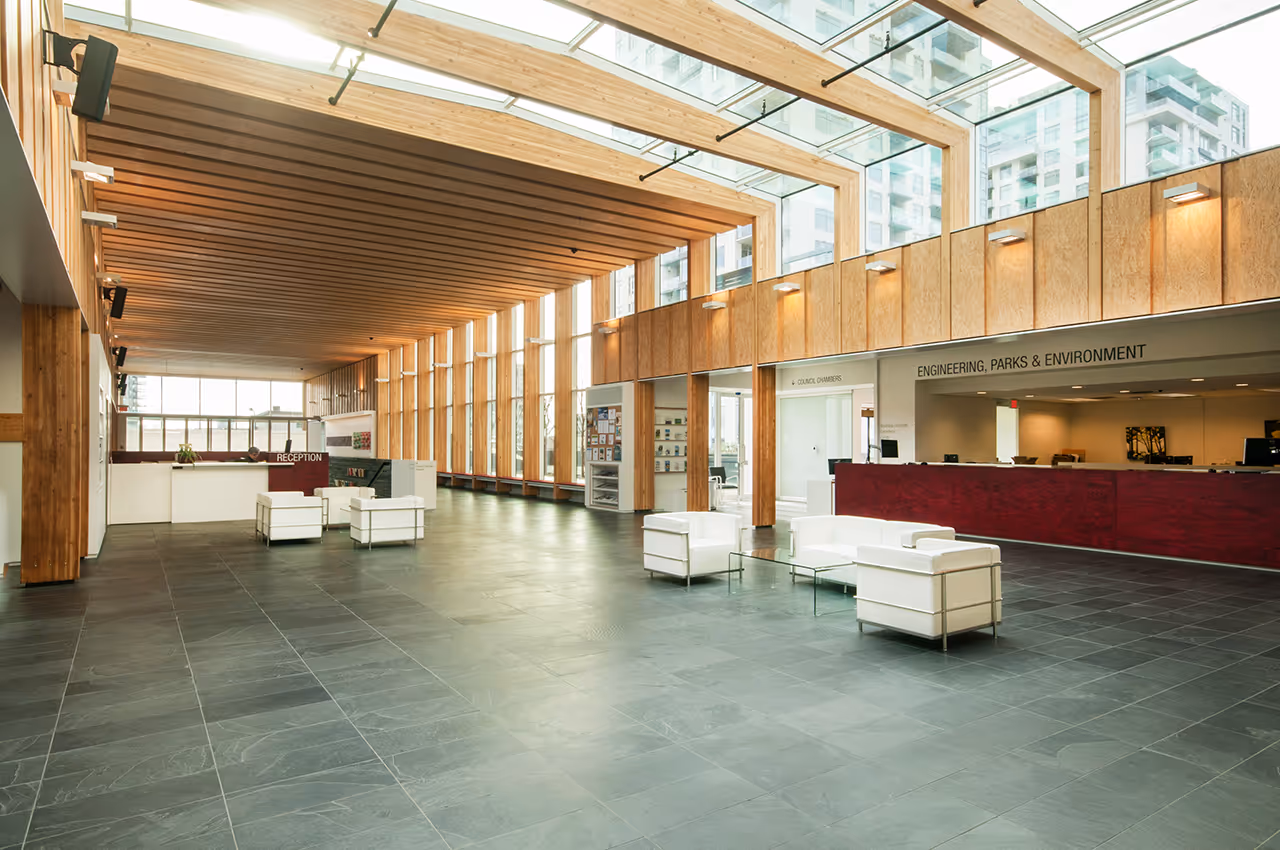 Main lobby of North Vancouver City Hall Redevelopment with timber ceiling, skylights, and reception desk.
