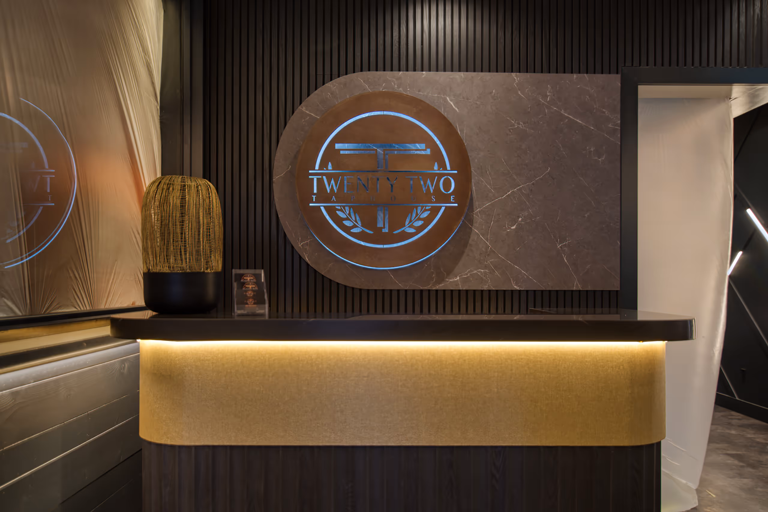 Twenty Two Taphouse reception desk with illuminated logo feature and architectural lighting design