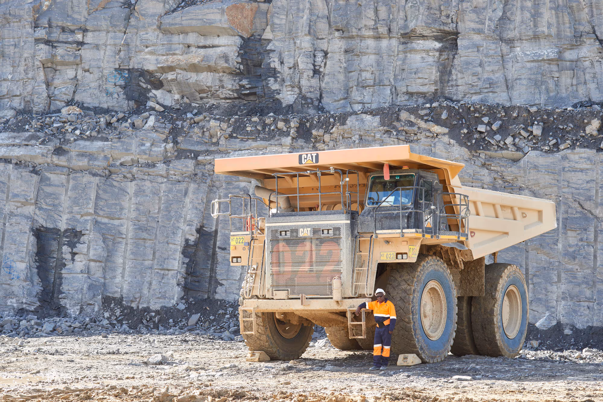 Large haul truck operating in the Otjikoto open-pit mine with worker standing beside the vehicle