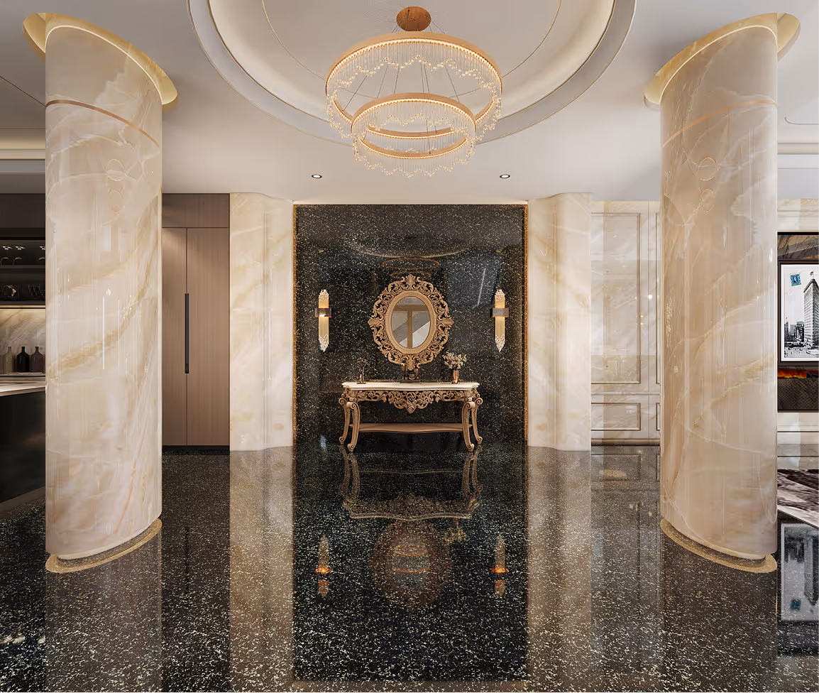 Luxurious interior with polished black terrazzo floor, two large cream marble columns, ornate gold-framed oval mirror above decorative console table, and modern circular chandelier.