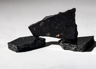 Three irregular pieces of black mica mineral with shiny surfaces on a white background.
