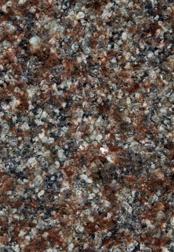 Close-up of polished granite surface with mixed reddish-brown, black, and light gray mineral grains.