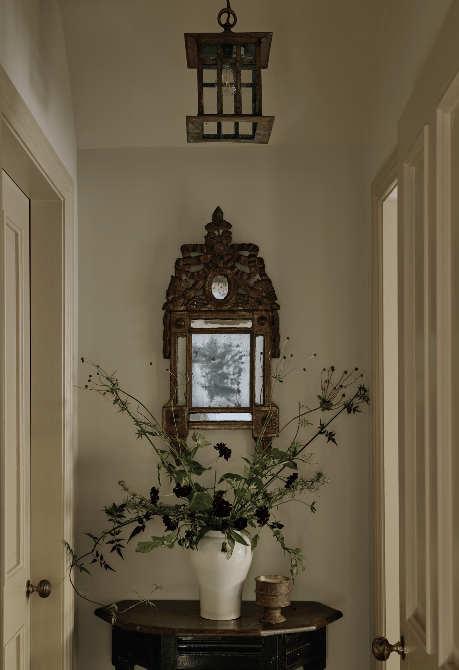 Garden House hallway with an antique mirror, console table and flowers