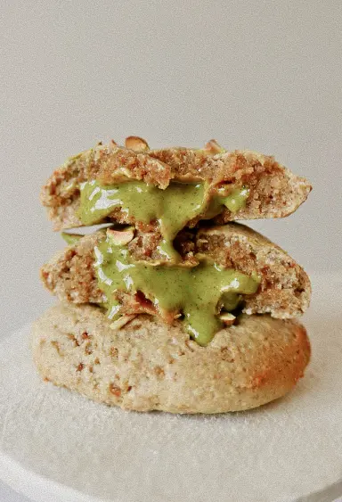 Cookie moelleux coupé en deux, avec un cœur fondant vert et morceaux de noix.