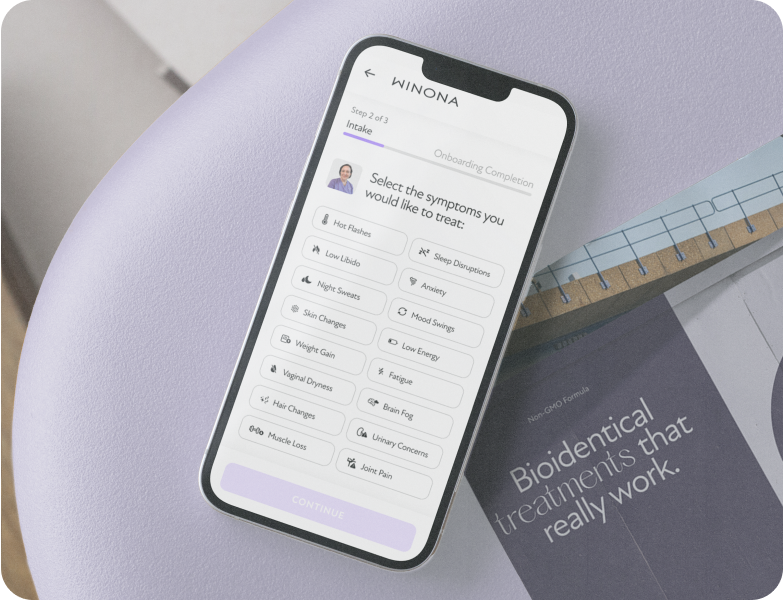Smartphone screen showing a symptom selection form for treatment with options like hot flashes, sleep disruptions, anxiety, and mood swings on a purple surface beside a brochure titled 'Bioidentical treatments that really work.'