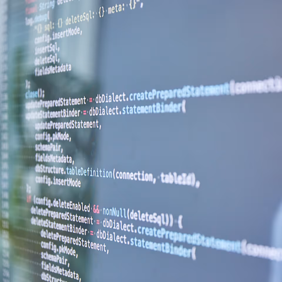 Blurred computer screen displaying lines of programming code in a soft-focus close-up.