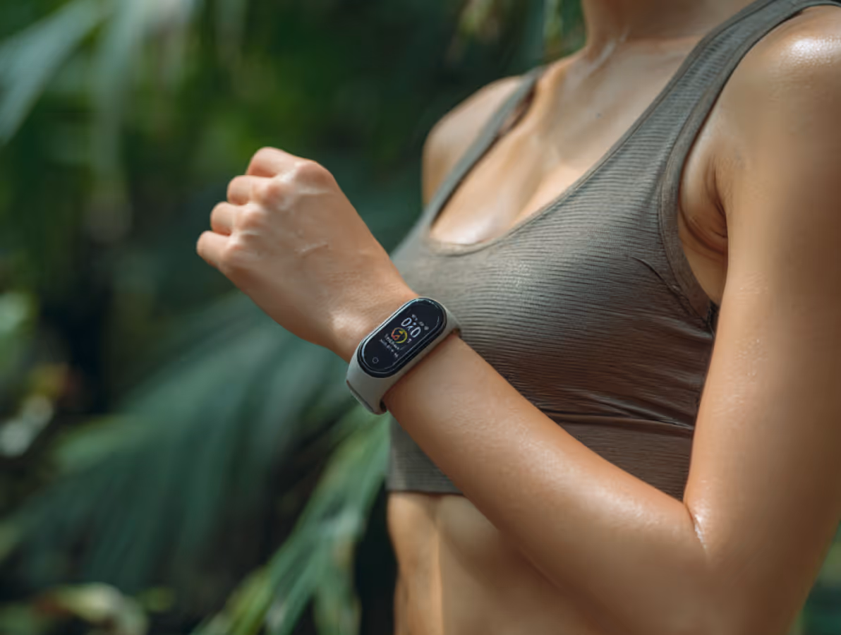 Close-up of a person in a sports bra wearing a fitness tracker on their wrist outdoors.