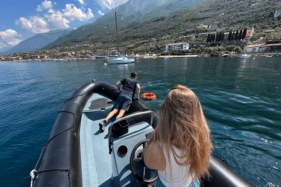 Frau steuert ein Schlauchboot auf dem Wasser, während ein Mann einen Rettungsring ins Wasser wirft.