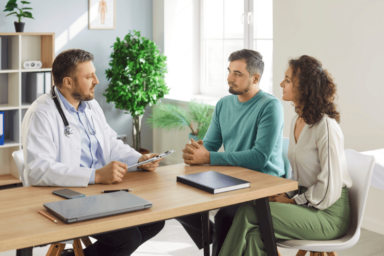 A couple speaking with a doctor in a medical office, discussing fertility preservation options before starting testosterone therapy.