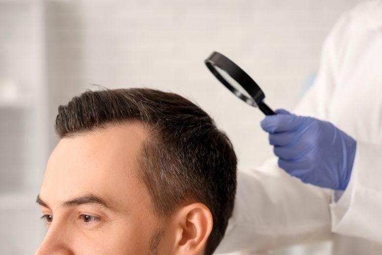 Man undergoing scalp examination while taking finasteride for hair loss treatment and monitoring potential sexual side effects. [Photo by pixelshot on Canva.]