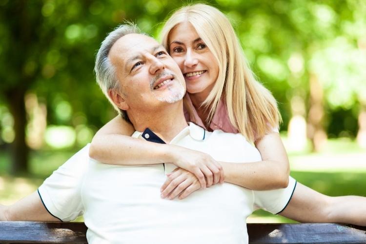 Blonde woman hugging grey-haired man in white shirt