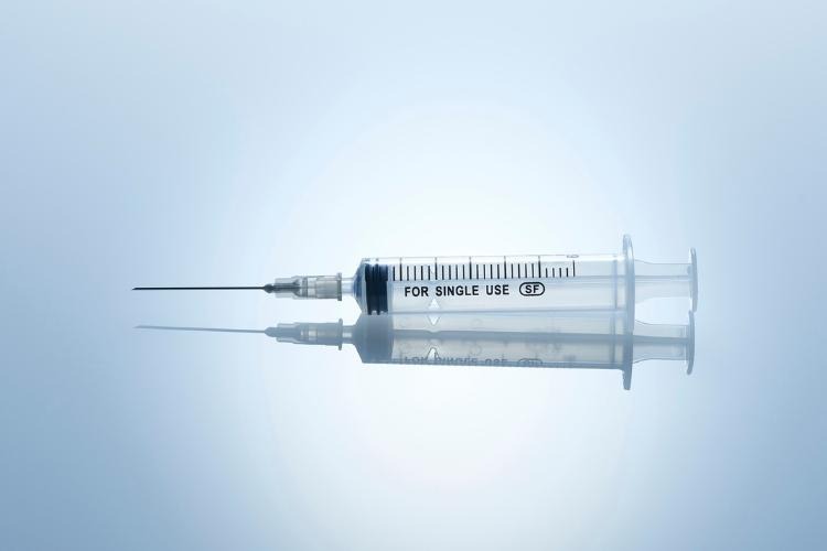 A single use syringe on a grey background