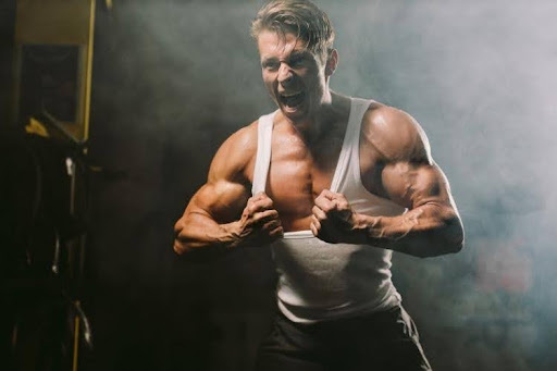 Angry muscular man pulling his shirt.