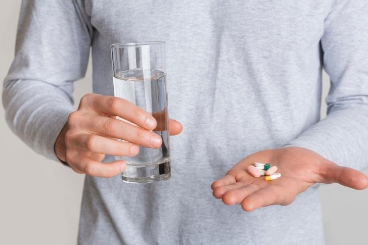 close up of man's hand with water and pills