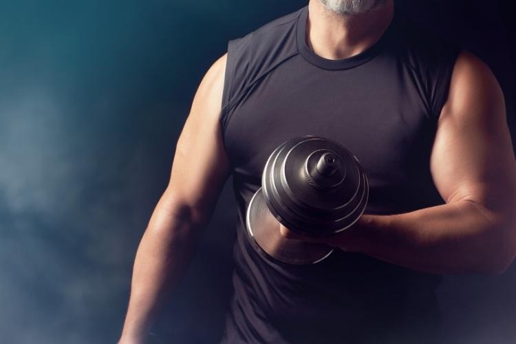 Older man lifting a dumbbell for strength training and muscle maintenance.