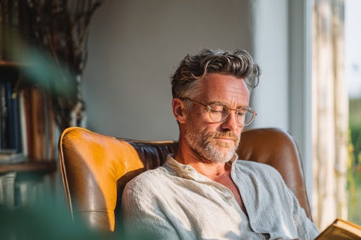 Middle-aged man reading at home to support cognitive health and mental activity.