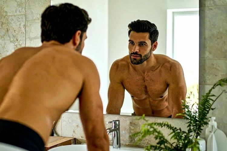 Man looking at himself in bathroom mirror.